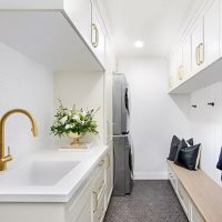 Luxury custom-designed mudroom by The Closet Butler with built-in cabinets, bench seating, and coat hooks.